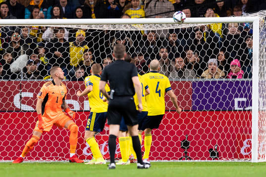 The ball hits the crossbar behind goalkeeper Robin Olsen of