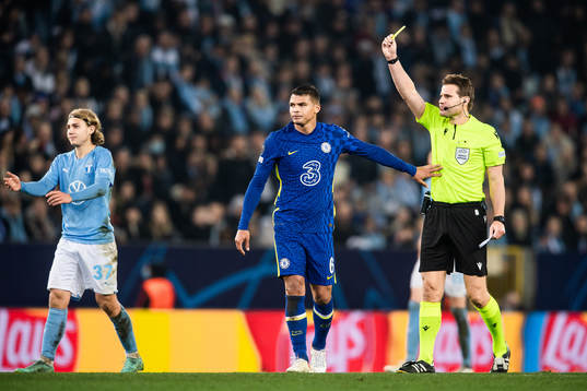 Referee Felix Brych shows Thiago Silva of Chelsea a yellow
