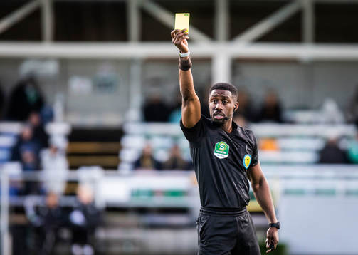 Domaren Fredrik Oppong delar ut ett gult kort