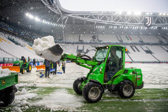 Workers clear the pitch from snow at Allianz Stadium