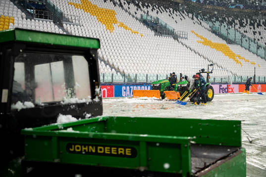 Workers clear the pitch from snow at Allianz Stadium