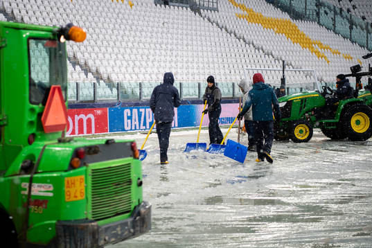 Workers clear the pitch from snow at Allianz Stadium