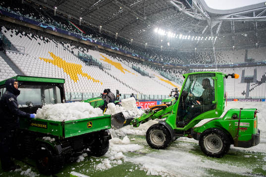 Workers clear the pitch from snow at Allianz Stadium