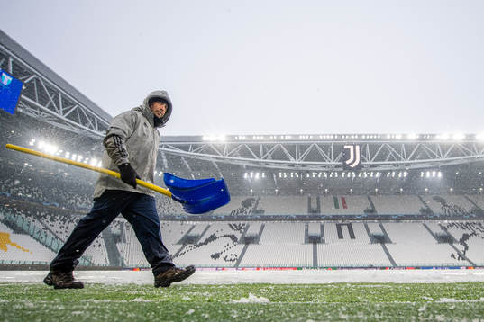 Workers clear the pitch from snow at Allianz Stadium