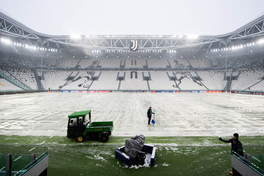 Workers clear the pitch from snow at Allianz Stadium
