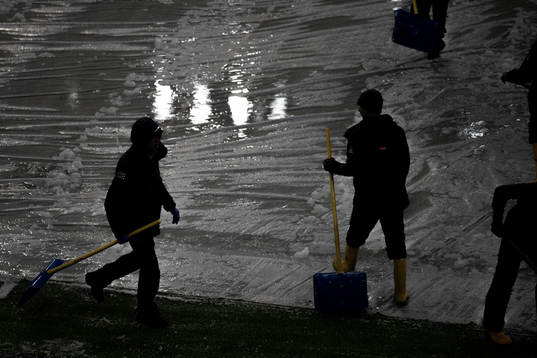 Workers clear the pitch from snow at Allianz Stadium