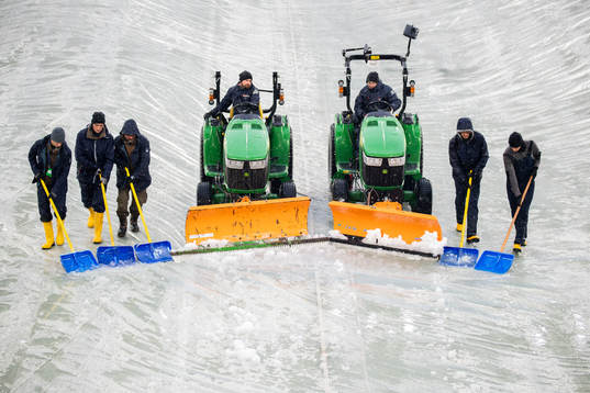 Workers clear the pitch from snow at Allianz Stadium