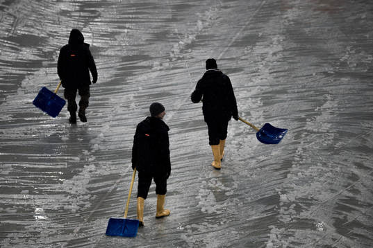 Workers clear the pitch from snow at Allianz Stadium