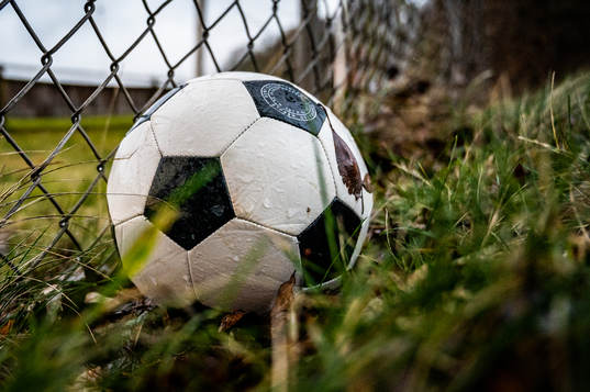 En fotboll ligger vid ett staket utanför en idrottsplats