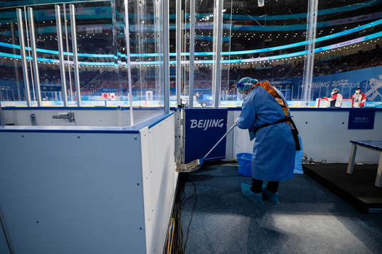 A worker in full-body protective gear (PPE) disinfects the