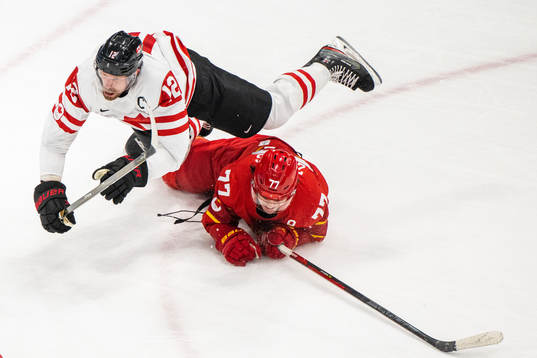 Eric Staal of Canada falls over Zheng Enlai of China in an