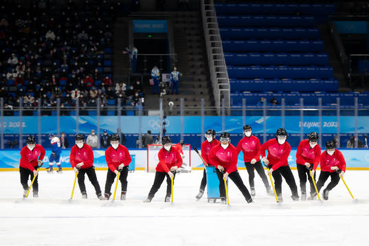 Volunteers cleans the ice in the men's ice hockey bronze