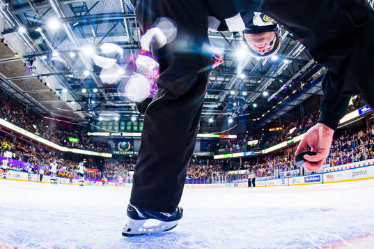 En domare plockar upp en puck ur målet