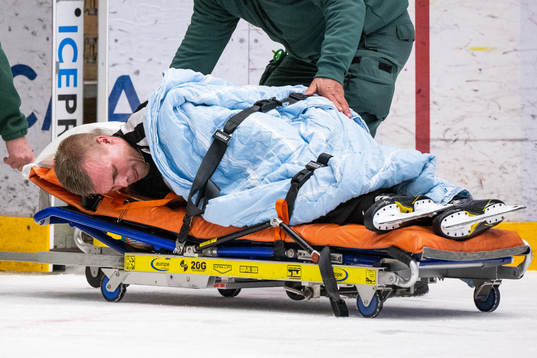 Linjedomare Tobias Nordlander körs ut på bår