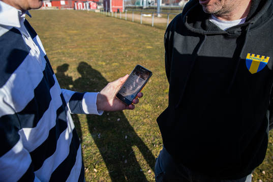 Tim Nielsen håller i en mobiltelefon med Torn IFs