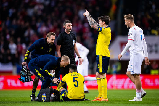 Martin Olsson of Sweden in pain as Victor Lindelöf signals