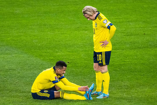 Martin Olsson of Sweden in pain next to Emil Forsberg