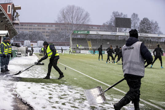 Funktionärer skottar snö innan fotbollsmatchen i