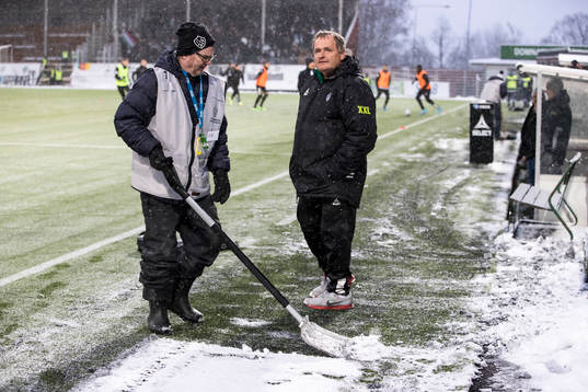 Funktionärer skottar snö innan fotbollsmatchen i