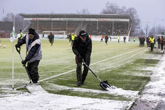 Funktionärer skottar snö innan fotbollsmatchen i