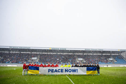 The players hold a «Peace Now!» sign