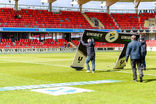 En raklamskylt blåser omkull före fotbollsmatchen i
