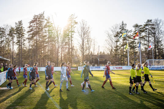 Båda lagens spelare gör entré till fotbollsmatchen i