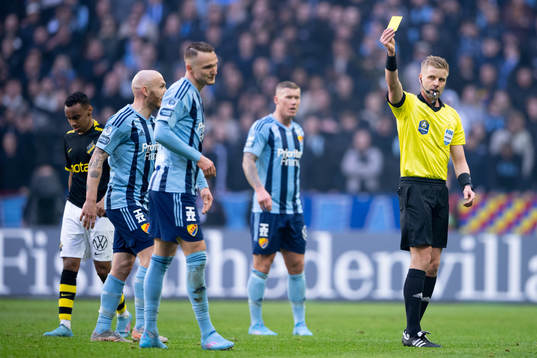 Domare Glenn Nyberg delar ut ett gult kort till
