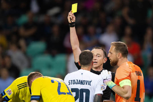 Petar Stojanovic of Slovenia receives a yellow card from