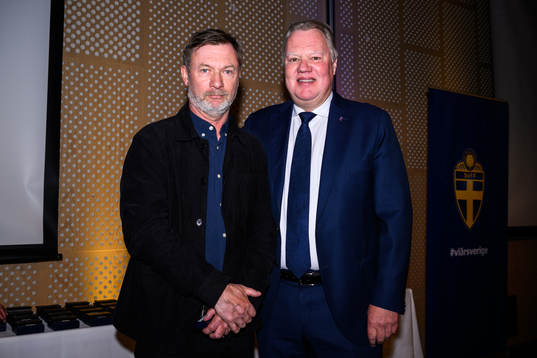 Peter Gerhardsson tar emot ett förtjänstmärke i guld