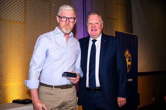 Roger Milton tar emot ett förtjänsttecken i guld