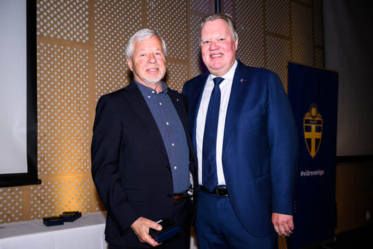 Gilbert Löfgren tar emot ett förtjänsttecken i guld