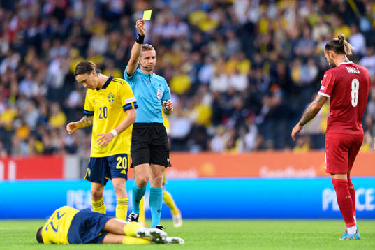 Referee Lawrence Visser shows a yellow card to Nemanja