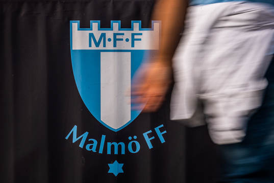 En person går förbi en Malmö FF-logotyp