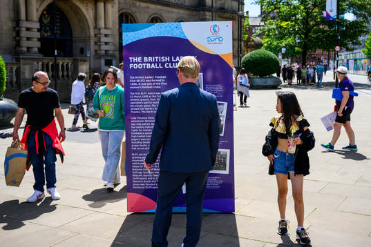 Bystanders pass billboards with information about the UEFA