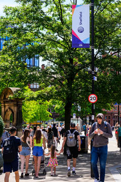 Bystanders pass billboards for the UEFA Women's Euro 2022