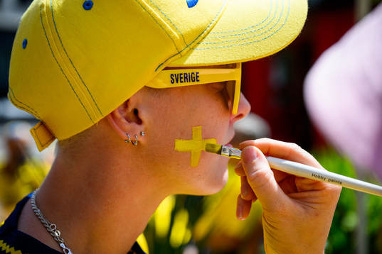 A supporter of Sweden gets the Swedish flag painted
