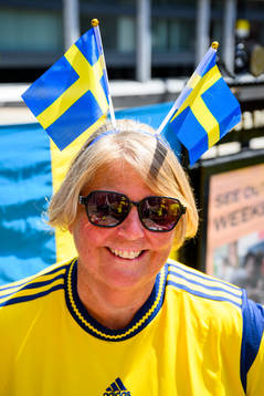 A supporter of Sweden with two Swedish flags in downtown