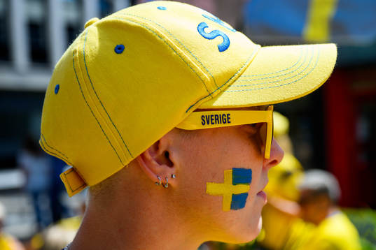A supporter of Sweden gets the Swedish flag painted
