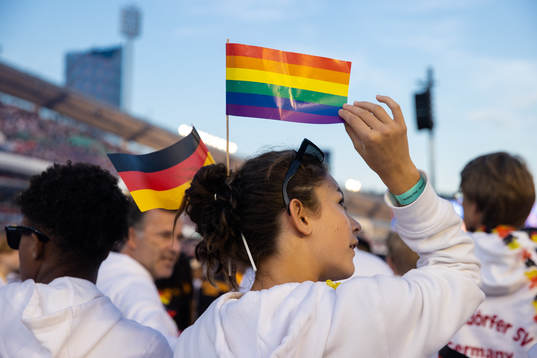En spelare med en tysk flagga och en pride flagga i håret
