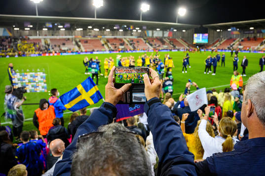 A spectator takes a photo of players of Sweden celebrating
