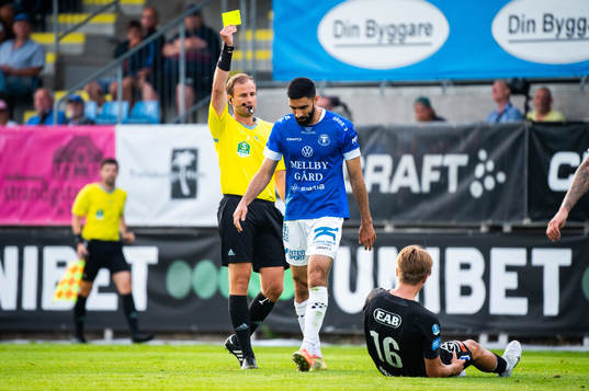 Domare Richard Sundell delar ut ett gult kort till