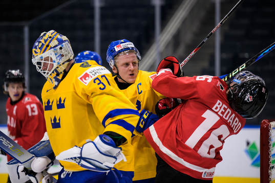 Emil Andrae of Sweden hits Connor Bedard of Canada