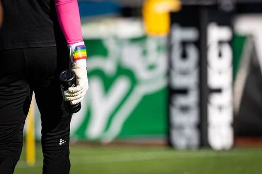 Fotbollshandskar med Pride flagga före fotbollsmatchen i