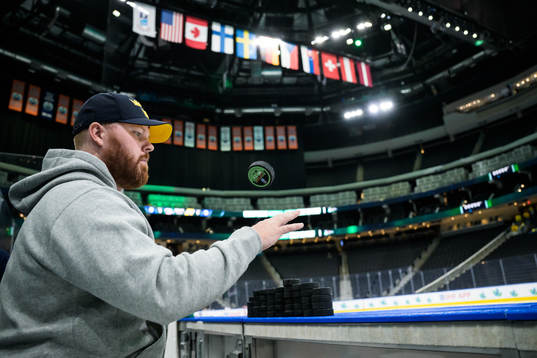 Equipment manager Andy Fagerström of Sweden flips a puck