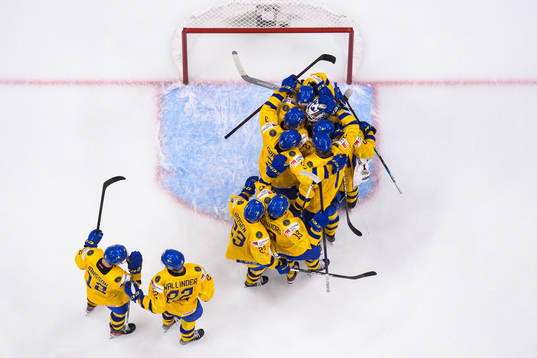 Players of Sweden congregate around goaltender Jesper