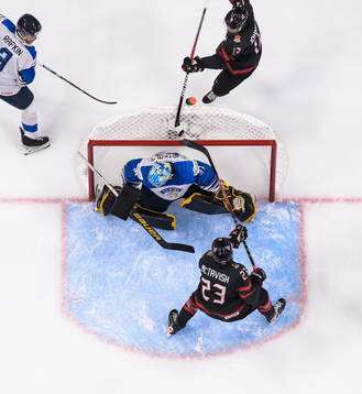 Kent Johnson and Mason McTavish of Canada try to score