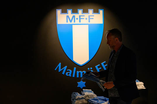 A man looks at scarfs in the supporter shop in front of the