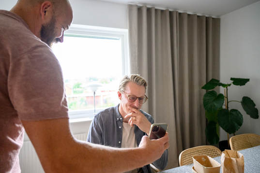 Sanny Lindström visar något på sin telefon för Oscar