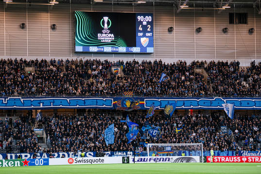 A big display shows the score behind the supporters of